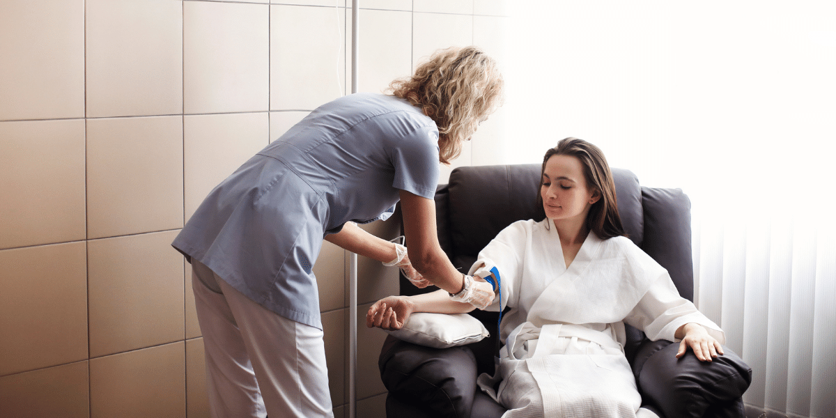 Female nurse administering IV in female patient