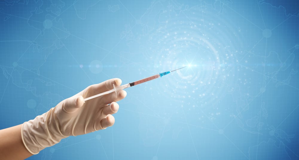 Female doctor hand holding syringe with blue background and shine